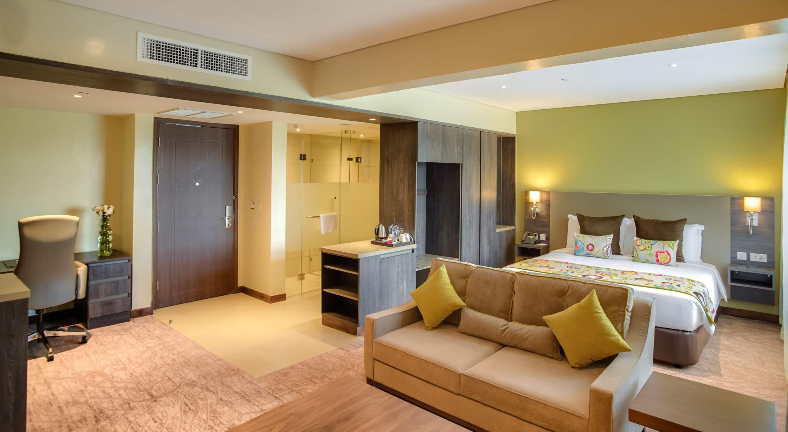 An Executive Suite at the Tamarind Tree Hotel in Nairobi, featuring a separate lounge area with a sofa and a rain shower.